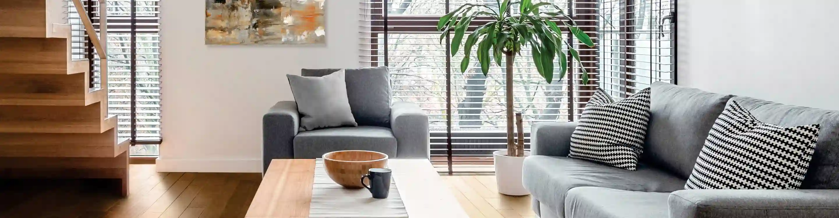 dark brown window treatment blinds in living area with grey furniture and light wood floors